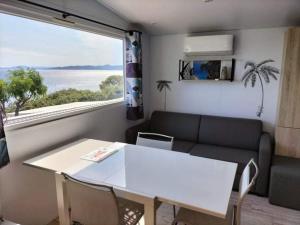 sala de estar con mesa, sofá y ventana en Charmant Mobil home avec Vue mer exceptionnelle, en Saint-Raphaël