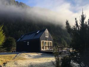 a black cabin in the middle of a mountain at Refugio Macales - Ecocabañas in Puerto Dunn