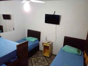 Habitación con 2 camas y TV de pantalla plana. en Hostel Gerais, en Belo Horizonte