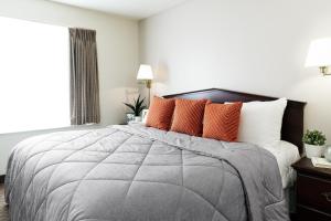 a bedroom with a large bed with orange pillows at InTown Suites Extended Stay Houston TX - Westchase in Houston