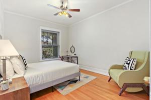 um quarto com uma cama, uma ventoinha de tecto e uma cadeira em Stylish and Expansive 2BR Apt with Balcony - Buckingham 3 em Chicago