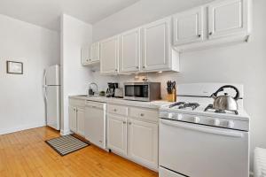 a kitchen with white cabinets and a white stove top oven at Stylish and Expansive 2BR Apt with Balcony - Buckingham 3 in Chicago