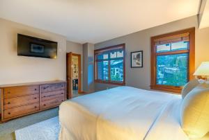 a bedroom with a bed and a tv and windows at Capitol Peak Lodge by Snowmass Mountain Lodging in Snowmass Village