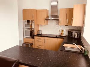a kitchen with wooden cabinets and a black counter top at Logan Home in Stornoway