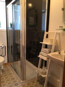 a shower with a glass door next to a sink at Logan Home in Stornoway