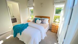 a bedroom with a bed with a blue comforter and two windows at Nottinghill B n B in Blenheim