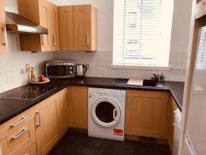 a kitchen with a washing machine and a microwave at Logan Home in Stornoway