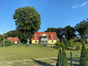 a large yellow house with a red roof at Poppes Ranch Bauerhof & Campingplätze in Zepelin