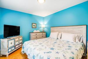 a blue bedroom with a bed and a flat screen tv at Oasis on 69th Street in Ocean City