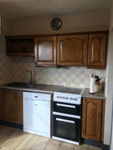 una cocina con electrodomésticos blancos y armarios de madera en Hillside Haven, en Tahilla