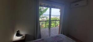 a bedroom with a bed and a window with a view at Aquarela Bombinhas in Bombinhas
