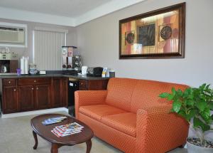 MERRIMAC INN & SUITES في وليامزبورغ: غرفة معيشة مع أريكة برتقالية وطاولة