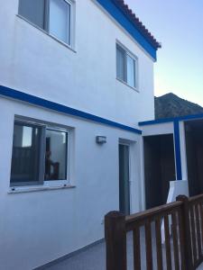 a white house with a blue stripe on it at Alo Baía São Lourenço in Santa Bárbara