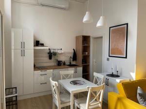 a kitchen and dining room with a white table and chairs at Apartments TEMA in Sombor