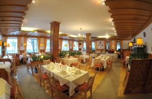 un restaurante con mesas y sillas blancas y ventanas en Seehotel Schlick, en Fuschl am See