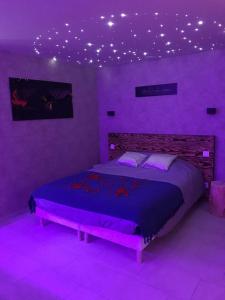 Dormitorio púrpura con cama con luces en el techo en Cosy Love & Spa Love room avec spa, hammam et sauna privatif en Cemboing