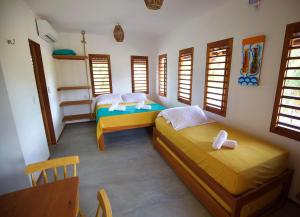 a room with two beds and a table and windows at Maluhia Lofts in Icaraí