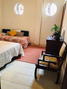 ein Schlafzimmer mit einem Bett und einem Stuhl sowie zwei Fenstern in der Unterkunft Guest House Nosso Aconchego in Teresópolis