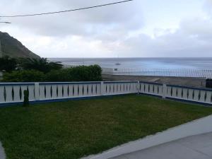 a view of the ocean from a house with a white fence at Alo Baía São Lourenço in Santa Bárbara