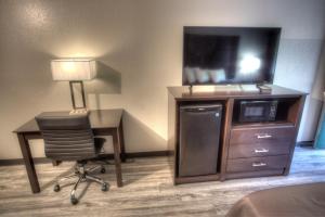 a hotel room with a desk and a tv and a chair at Budgetel Inn and Suites Plus Helen in Helen