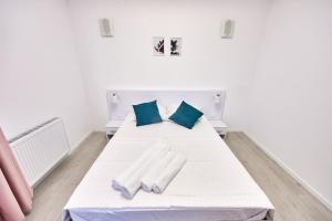 a white bed with two blue pillows on it at AnaApartaments in Năvodari
