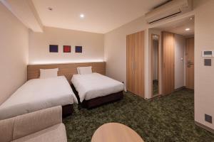 a hotel room with two beds and a couch at S-Peria Hotel Fukuoka Nakasu in Fukuoka