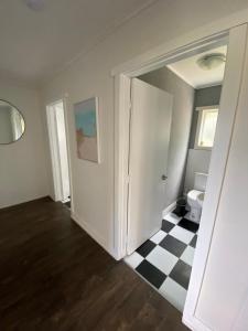 ein Badezimmer mit einem WC und einem schwarz-weiß karierten Boden in der Unterkunft Home and cottage for a family break away in Paihia