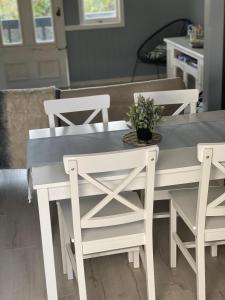 ein weißer Esstisch mit weißen Stühlen und einem blauen Tisch in der Unterkunft Home and cottage for a family break away in Paihia