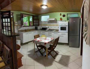 a kitchen with a table and a stove and refrigerator at Chez Marie André et Jeanne in Grande Anse