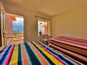 a bedroom with a colorful striped bed and a window at Richar’s home - experience Amantani with my family in Ocosuyo
