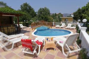 ein Schwimmbad mit weißen Stühlen und einer Reihe von Büros in der Unterkunft Agali Hotel in Limenaria