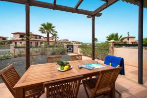 a wooden table with chairs and a bowl of fruit on it at Pierre & Vacances Resort Fuerteventura OrigoMare in Lajares