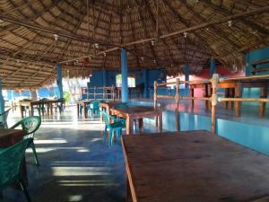 un restaurant avec des tables et des chaises sous un toit de paille dans l'établissement Hotel Pez de Oro, à Monterrico