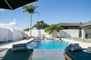 a swimming pool with people in the water at Mysa Yamba - oceanstays in Yamba