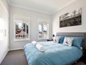 - une chambre avec un lit bleu et 2 fenêtres dans l'établissement Winsome, à Blackheath