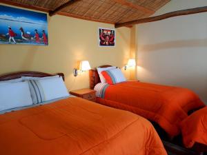 two beds in a hotel room with orange sheets at Wara Uta Lodge in Comunidad Yumani