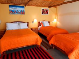 Comunidad YumaniWara Uta Lodge的房间里有两张床，床单是橙色的