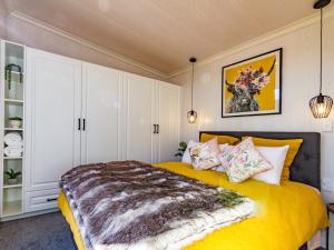 Mangateitei Views - Rangataua Tiny Home في أوهاكيون: غرفة نوم بسرير اصفر ودواليب بيضاء