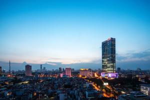 une vue sur la ville la nuit avec un haut gratte-ciel dans l'établissement Lotte Hotel Hanoi, à Hanoï