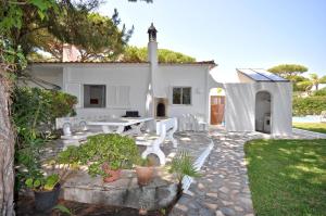 a backyard with a white house with a table and chairs at Delightful single-storey villa, private pool, free air conditioning and wifi in Vilamoura