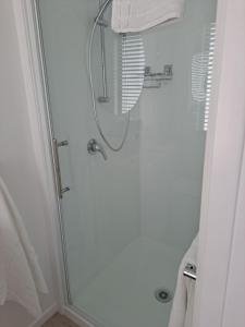 um chuveiro com uma porta de vidro na casa de banho em Pod bach on Tweed em Tauranga