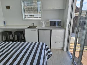 uma cozinha com armários brancos e uma bancada em Pod bach on Tweed em Tauranga