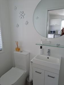 a white bathroom with a sink and a mirror at Pod bach on Tweed in Tauranga