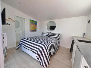 a bedroom with a black and white striped bed at Pod bach on Tweed in Tauranga