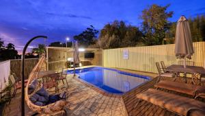 a pool with chairs and a hammock next to a fence at Sun Centre Motel in Swan Hill