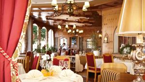 un ristorante con tavoli e sedie bianchi e un lampadario a braccio di Seehotel Schwan a Gmunden