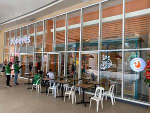 a restaurant with tables and white chairs in front of a store at Will’s Place at Jazz Makati in Manila