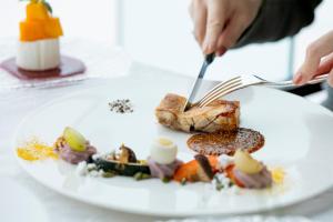 een persoon die eten op een bord met een vork en mes bij The Windsor Hotel TOYA Vignette Collection in Lake Toya