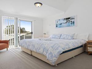a white bedroom with a bed and a large window at Bay Views in Callala Bay