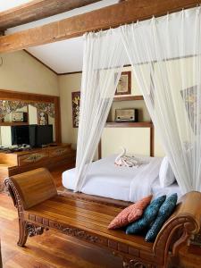 a bedroom with a canopy bed with a bench at Sapulidi Cafe, Gallery & Resort in Lembang